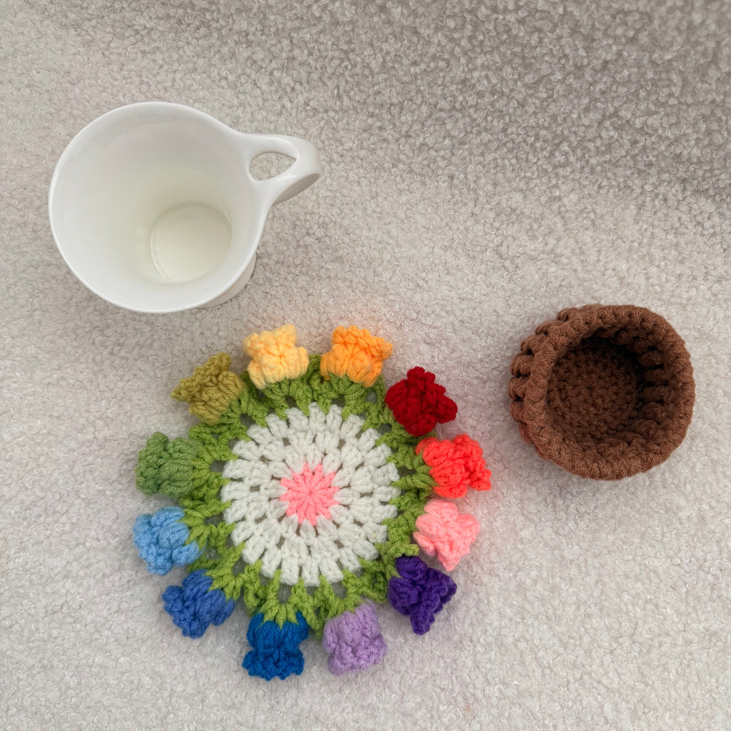 Colorful crocheted coaster with a white cup on a textured surface
